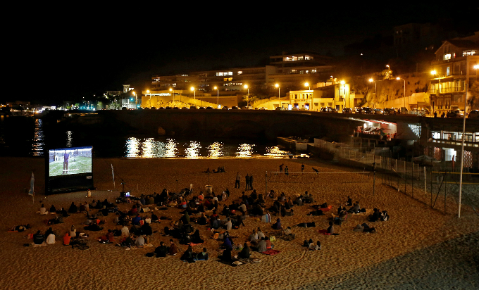 People watch a movie on a beach at night in Marseille, France.